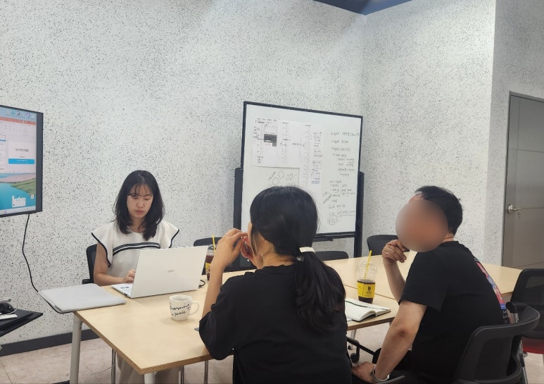 화이트보드에 광고 구조를 정리해 두고 기업 담당자 두 명과 진행하는 마케팅팀 광고 교육 현장