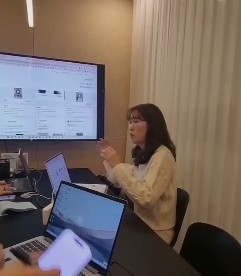 대형 모니터에 홈페이지 화면을 띄우고 유입 경로 설계를 설명하는 사내 마케팅팀 광고 교육 장면
